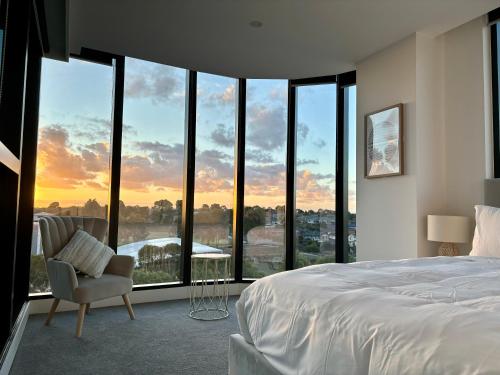格伦韦弗利Skygarden Luxury Condo的卧室配有一张床铺和一张椅子,位于窗户前