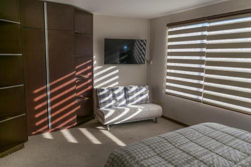拉巴斯HB Apartament Sopocachi的一间卧室配有一张床、一把椅子和电视