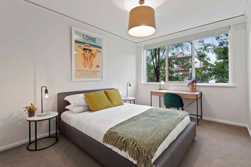墨尔本Urban Retro - Experience Vibrant Courtyard Charm的一间卧室配有一张床、一张书桌和一个窗户。