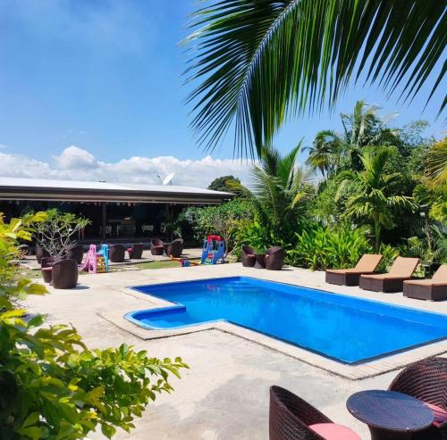 南迪Nadi Fancy Hotel的度假村内的游泳池,带椅子和棕榈树