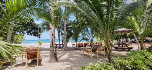 NauhangSulu Sunset Beach Resort的棕榈树海滩,沙滩上摆放着桌椅