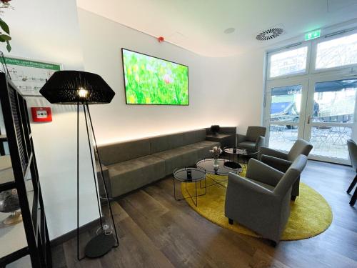 柏林HOLI City Apart Hotel Berlin的客厅配有沙发和墙上的电视