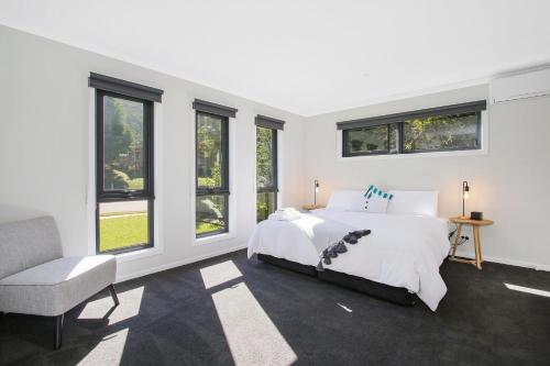 布赖特Snowgum Bright Retreat - 1的一间卧室配有一张床、一把椅子和窗户。
