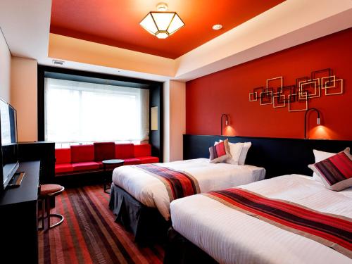 大阪Hotel Dans Le Coeur Osaka Umeda的红色墙壁的酒店客房内的两张床