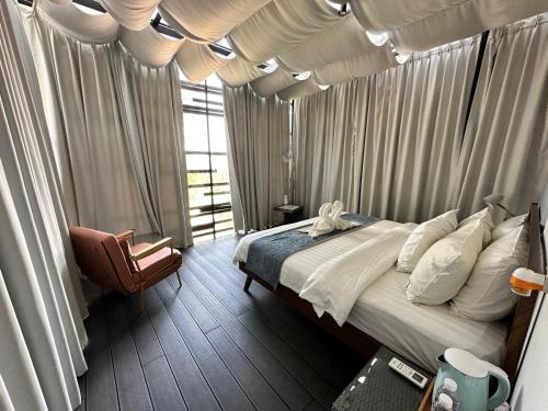 古晋涵洞度假村的一间卧室配有带窗帘的床和椅子