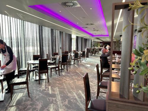 爱丁堡Tynecastle Park Hotel的一间配备有桌椅和紫色照明的用餐室