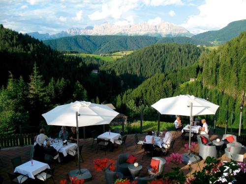 新波南特格尼斯可杰霍夫山温泉度假酒店的庭院配有桌子和遮阳伞,背景为山脉