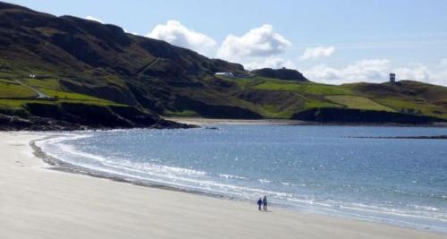 邓格洛Dungloe Lakeside Lodging的站在水边的海滩上的人