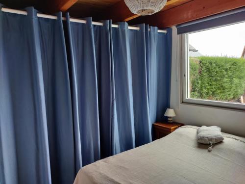 卡布尔Maison calme et lumineuse de plain-pied的一间卧室配有蓝色窗帘、一张床和窗户