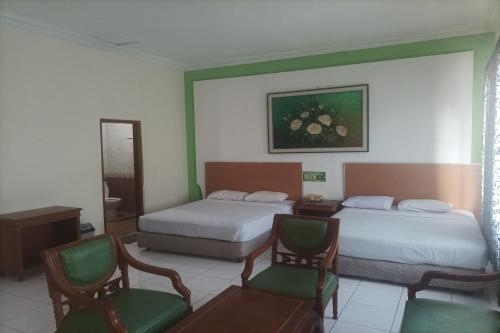 井里汶Permata Hijau的酒店客房,配有两张床和两把椅子