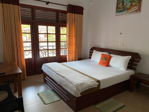 阿努拉德普勒Why Not Palace的一间卧室配有一张带橙色枕头的床
