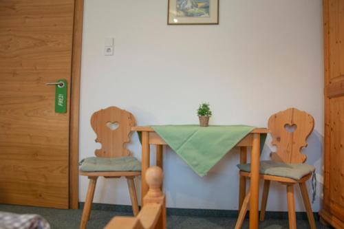 格伦Gästehaus Familie Gebhard Schädle的一张桌子和两把椅子,上面有绿桌布