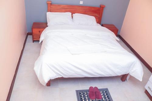 MeruTamwe ltd agency的卧室配有一张床铺,地板上放着两双红色鞋
