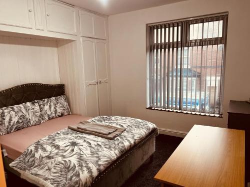 诺丁汉Holiday House Near Football Ground的一间卧室配有一张床、一张桌子和一个窗户。