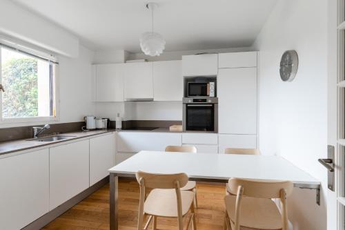 多维尔Magnificent 8P2BR apartment with indoor pool and garden - Deauville的厨房配有白色橱柜和桌椅