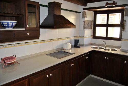 阿古伊梅斯Casa Rural El Cura的厨房配有木制橱柜、水槽和窗户。