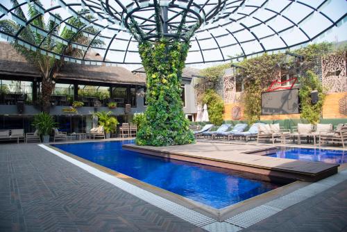 拉各斯Vertigo Hotel的一座带玻璃天花板和树的建筑中的游泳池