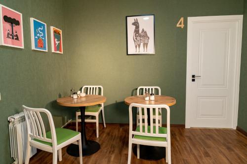 阿拉木图Evergreen Hostel的绿墙客房中的两张桌子和椅子