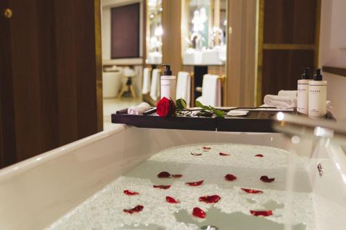 阿姆斯特丹INK Hotel Amsterdam - MGallery Collection的浴室配有浴缸,铺有红色玫瑰花瓣