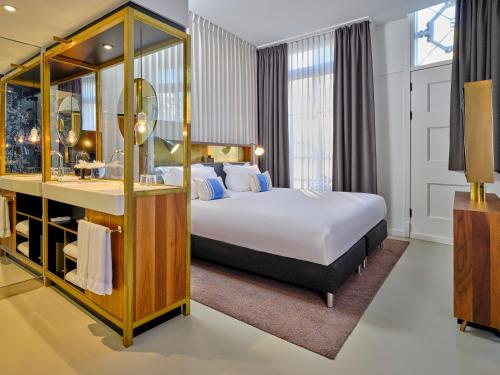 阿姆斯特丹INK Hotel Amsterdam - MGallery Collection的配有一张床和一张书桌的酒店客房