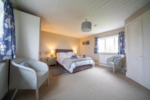 布德Penrose Cottage的一间卧室配有一张床、两把椅子和一个窗户