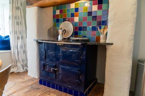 布德Penrose Cottage的厨房里有一个旧炉子,有五颜六色的瓷砖