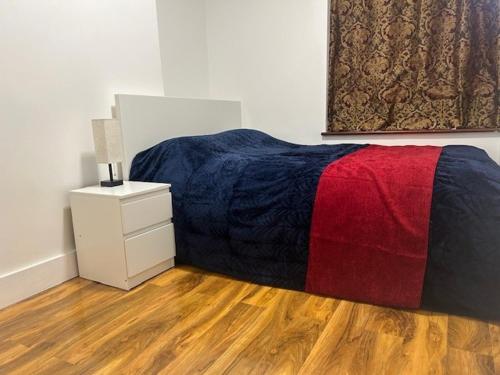 伦敦London Holiday Home的一间卧室配有一张带红色和蓝色毯子的床