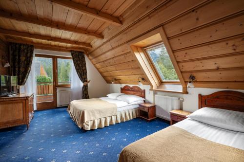 扎科帕内Hotel Belvedere Resort&SPA的一间带两张床的卧室,位于木天花板的房间