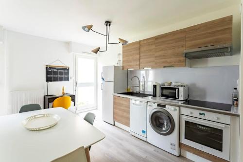 雷恩Les Asturies - Appartement rénové - Cosy moderne的厨房配有洗衣机和桌子