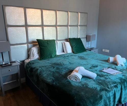 Longhope农场男孩宾馆的一间卧室配有一张带两条毛巾的大型绿床