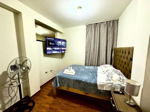 利马200. Hermoso Departamento con Servicios Incluidos en Chorrillos的一间卧室配有一张带风扇的床铺和一台电视机。