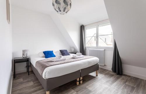 圣马洛Les Amarres - Maison familiale 3 chambres - Jardin的一间卧室配有一张带蓝色枕头的床和一扇窗户。