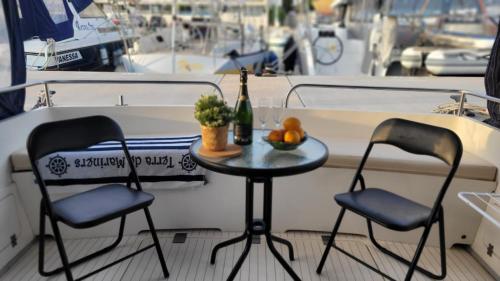 巴塞罗那Cosy and Homey Houseboat Castelldefels的一张桌子和两把椅子,船上一瓶葡萄酒