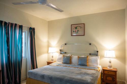 蒙特哥贝Ocean View King Room at Sahara Hotel的一间卧室配有一张带蓝色床单的床和两盏灯。