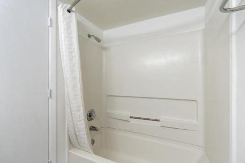 默特尔比奇美人鱼旅馆的浴室配有白色浴缸和淋浴。