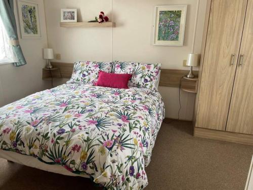 佩文西23 The Lawns Pevensey Bay Holiday Park的一间卧室配有一张带花卉床罩的床