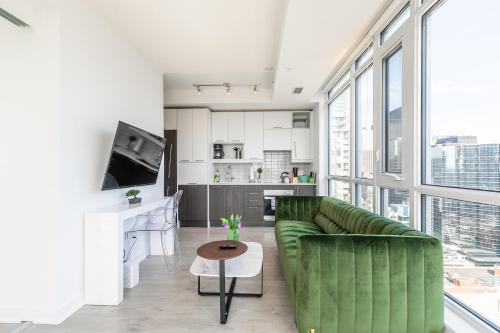 多伦多Executive Suites - Toronto's Entertainment District的一间带绿色沙发的客厅和一间厨房