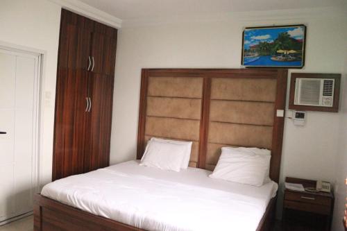 哈科特港Rocket Room Hotel & Suites Limited的卧室配有白色的床和木制床头板