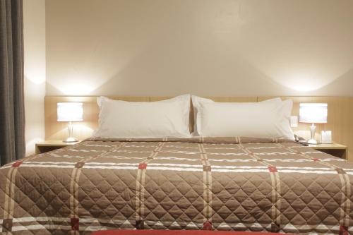 戈亚尼亚Castelo Inn Hotel的一间卧室配有一张大床和两盏灯