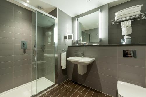 伦敦伦敦帕丁顿美居酒店的一间带玻璃淋浴和水槽的浴室