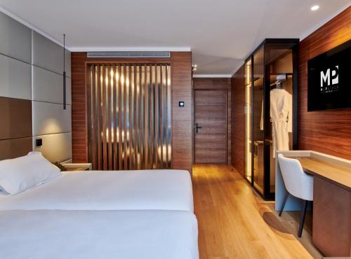 莱昂Hotel MyPalace León的卧室配有白色的床、书桌和衣柜。
