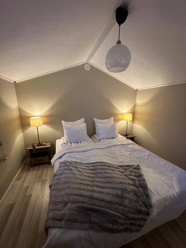 RobertsforsStuga med havsutsikt的一间卧室配有一张带两盏灯的大型白色床。