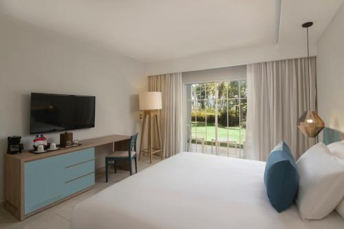拉斯加勒拉斯Wyndham Alltra Samana All Inclusive Resort的酒店客房配有一张床和一张书桌及一台电视