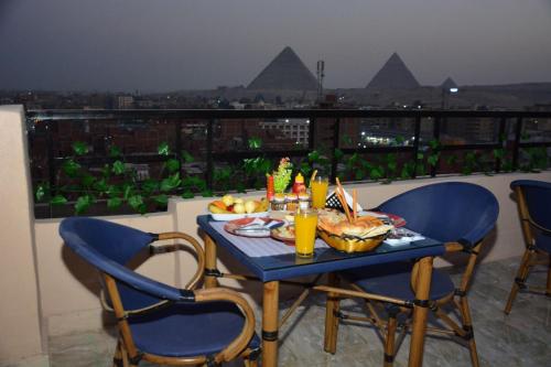 开罗Sneferu Pyramids inn - Full Pyramids View的阳台上的桌子上摆放着食物和饮料
