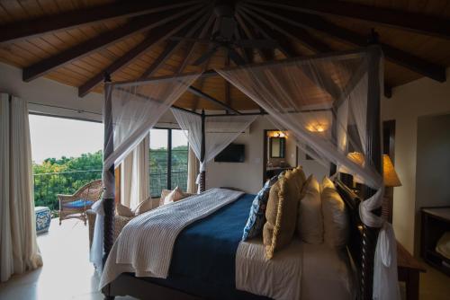 西班牙镇On The Rocks Villa的一间卧室设有一张带大窗户的天蓬床