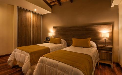 拉库布蕾Hotel Intersur La Cumbre的一间卧室设有两张床和木墙