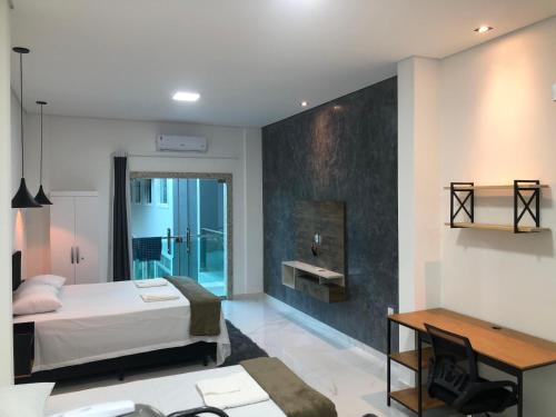伦索伊斯Lençóis Prime Apartments的一间卧室配有一张床、一张桌子和一个水槽