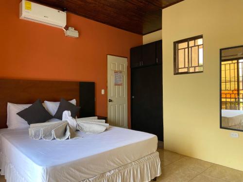 埃斯特利Hospedaje Coffee and cocktails的一间卧室配有一张白色的床和橙色的墙壁