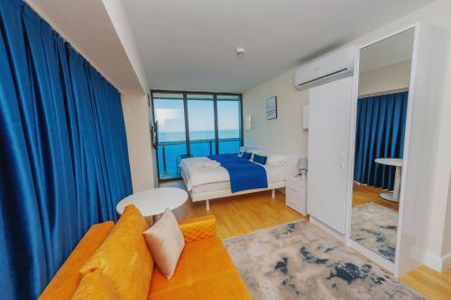 巴统Orbi City Sea View的一间卧室配有沙发和一张带蓝色窗帘的床