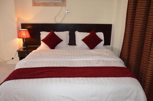 奥朱贝尔شقق آن للشقق المخدومة的卧室配有带红色枕头的大型白色床